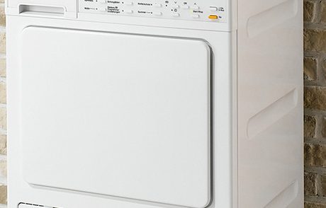 Uscător de rufe Miele T8976WP alb, cu panou de control și prosoape pe vârf.