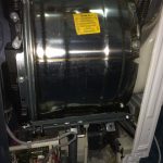 Motor de spălat cu tambur metalic și componente interne vizibile, inclusiv cabluri și plăci de circuit.