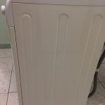 Mașină de spălat rufe albă cu un design simplu, vizibilă din lateral.