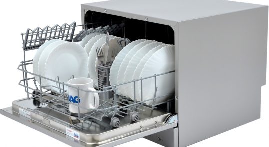 Mașină de spălat vase mică cu farfurii și ustensile în interior.