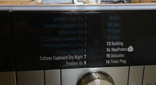Panou de control al unei mașini de spălat cu diverse programe de spălare listate.